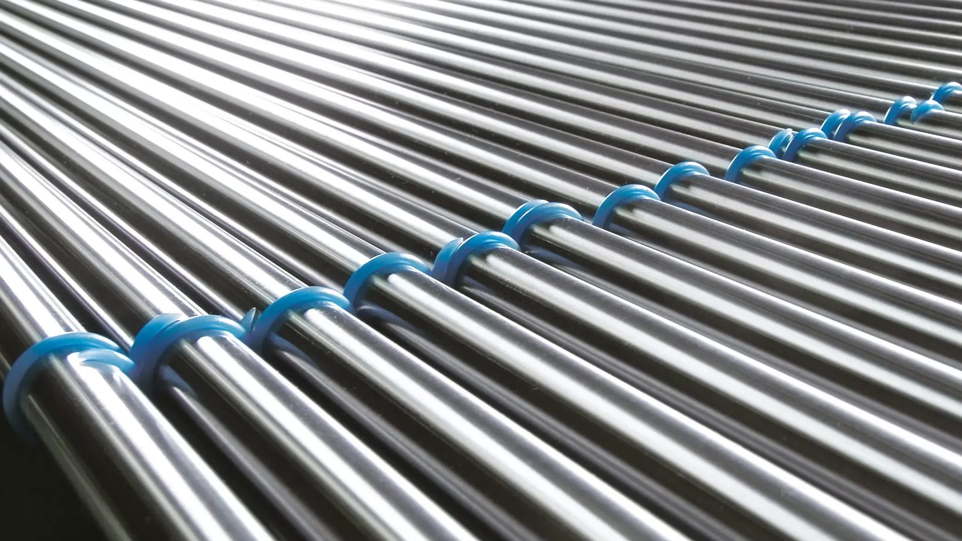 Rostfreier Stahl Stäbe mit blauen Abstandhaltern in einer Reihe für Industrieanwendungen.