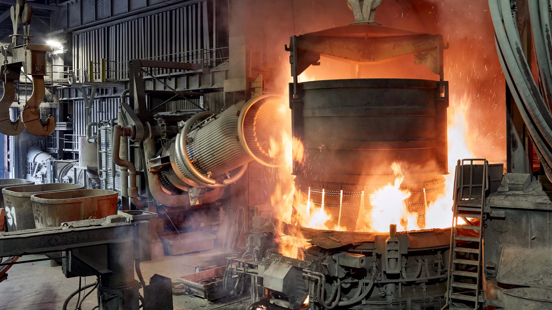 Korb voller Schrott wird in einen Elektrolichtbogenofen zur Einschmelzung geladen Funkenflug, Prozess der Stahlerzeugung