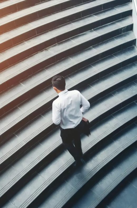 Geschaeftsmann steigt Treppe im Buerogebäude auf