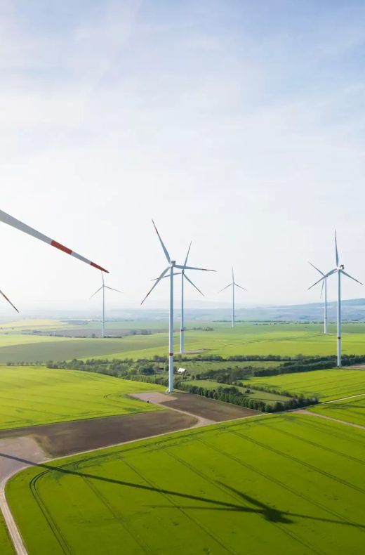 Luftaufnahme eines Windparks mit mehreren Windkraftanlagen auf einem grünen Feld für erneuerbare Energie und nachhaltige Entwicklung.